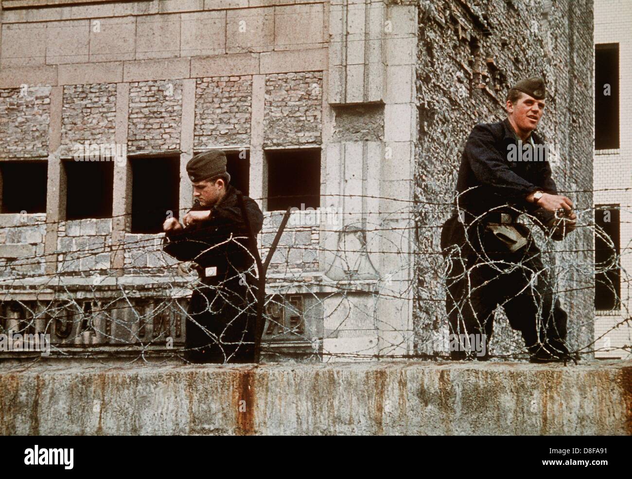 Volkspolizisten verstärken 1962 den Stacheldraht auf der Berliner Mauer. Am frühen Sonntagmorgen des 13. August 1961 wurde unter der Aufsicht von bewaffneten Streitkräften der DDR mit der Errichtung von Straßensperren aus Stacheldraht und dem Bau einer Mauer begonnen, um den Ostteil Berlins vom Westteil abzusperren. Die Mauer sollte den ständig steigenden Flüchtlingsstrom von Ost- nach West-Berlin stoppen. Stock Photo