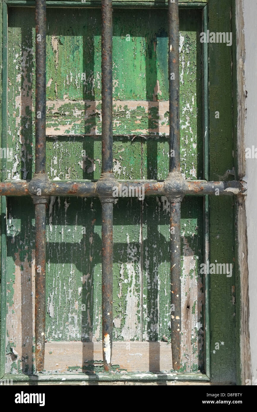 Rusty bars  across window shutters on old military building, Es Castell, Menorca, Spain Stock Photo