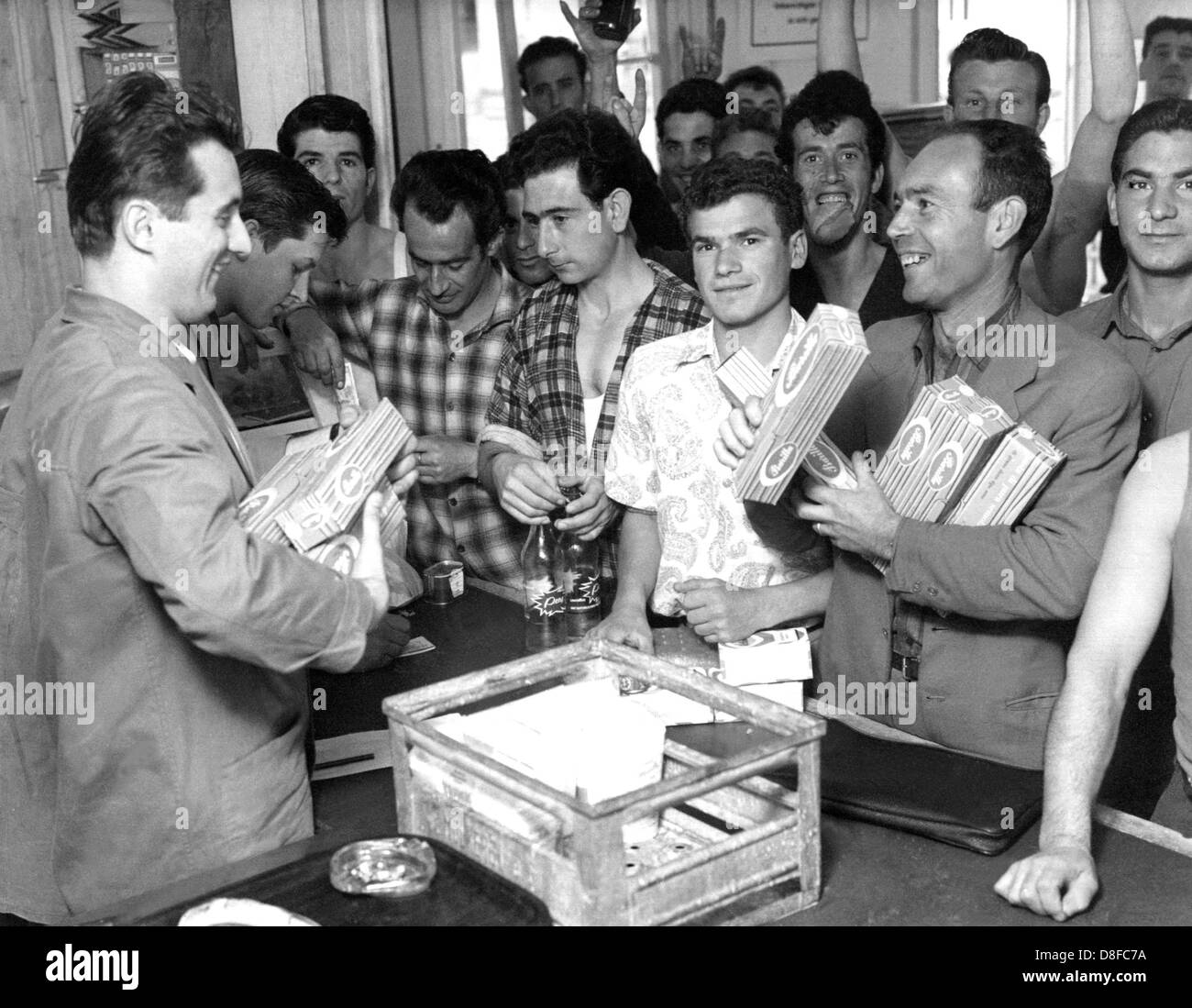 A group of Italian Gastarbeiter (especially guest workers in Germany in the 1960s and 1970s) buy spaghetti in Wolfsburg in 1962. Stock Photo