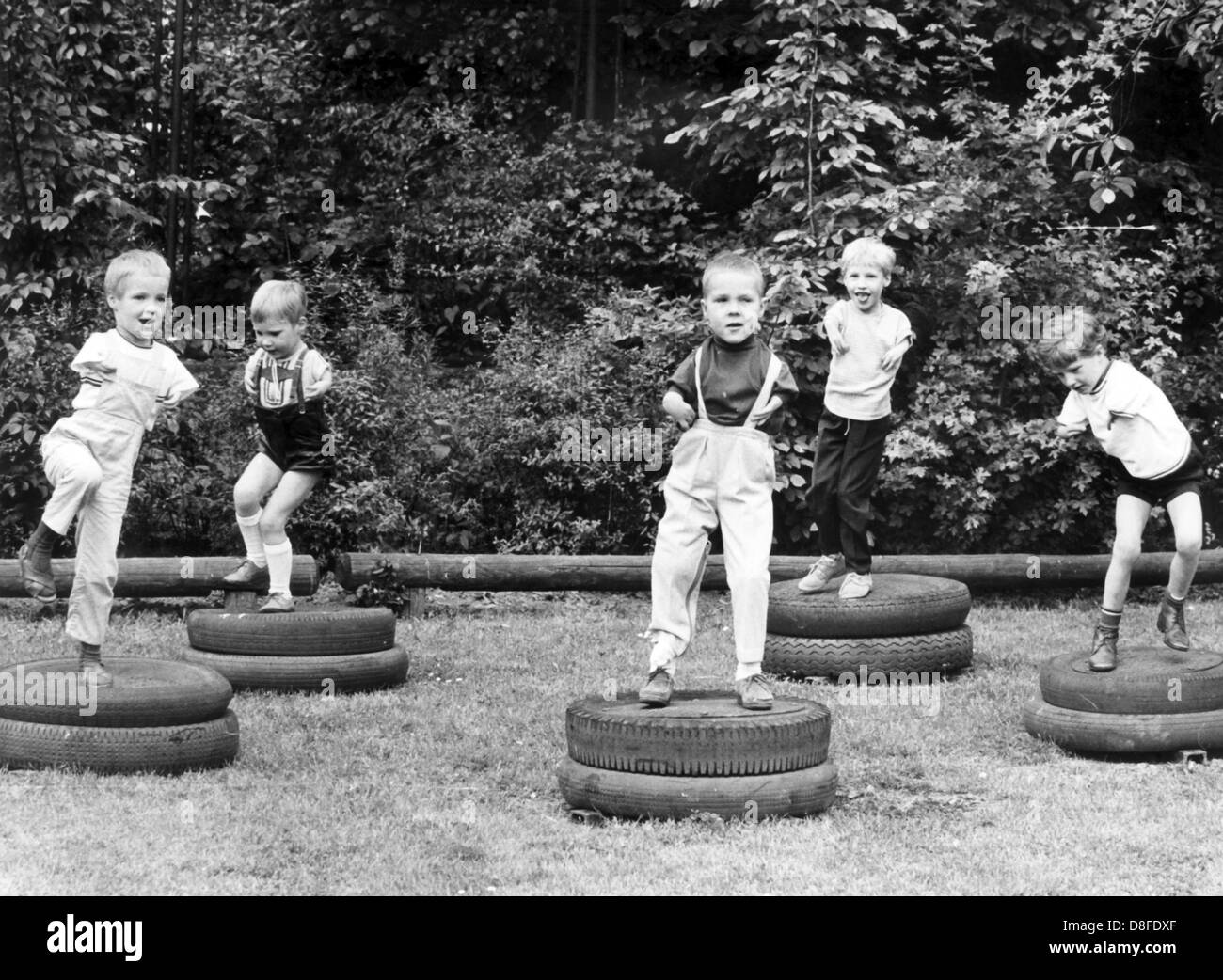 Contergan affected children jump around on tires at the playground of the city run day care center for children suffering from dysmelia in the Klettenberg district in Cologne, Germany, 24 March 1968. The facility prepares physically handicapped children for a future live with healthy children. Stock Photo