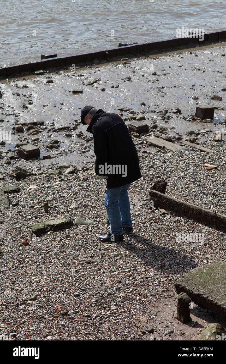 Man wearing hat searching on foreshore at low tide, River Thames, London Stock Photo