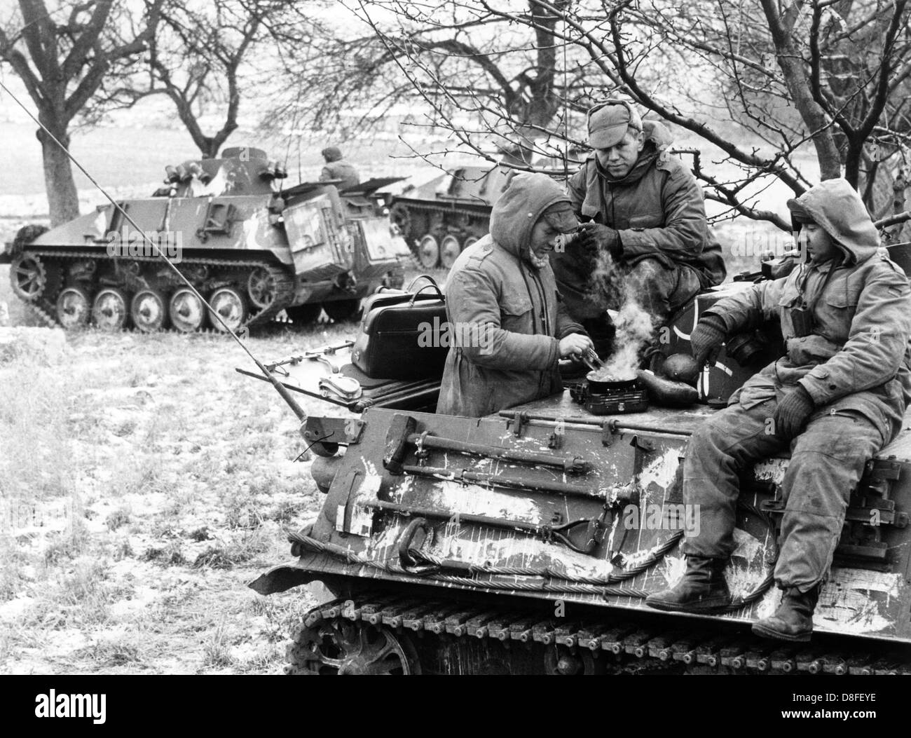 German soldiers of the Federal armed forces prepare a meal on their tank, while comrades keep guard combat-ready, near Tauberbischofsheim on the 10th of January in 1966. The soldiers and the tank are part of the German-American manoeuvre 'Silberkralle', in which 22,000 soldiers of the 3rd US tank division and 3,000 German soldiers of the 15th tank brigade Koblenz were involved. Stock Photo
