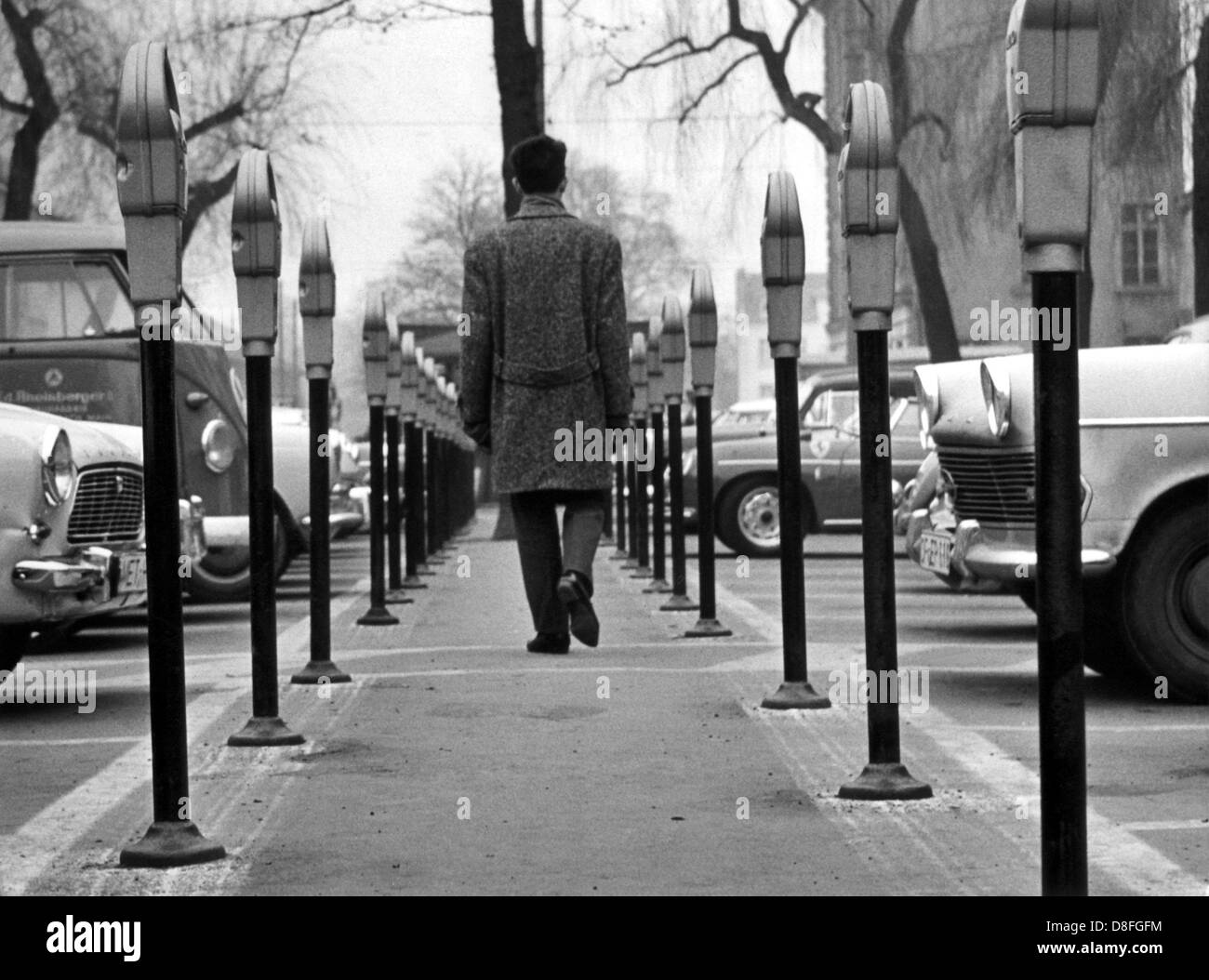 A pedestrian walks past parking meters in Frankfurt am Main on the 14th of March in 1964. Stock Photo