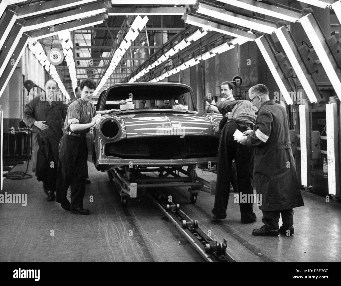 Employees work at the first Opel on the assembly line in the newly built part of the factory of the Opel works in Ruesselsheim in March 1960. Stock Photo
