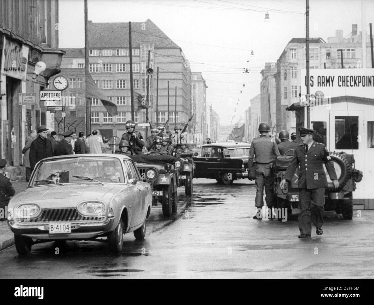 A limousine with US officers passes at Checkpoint Charlie from East to West Berlin, Germany, 25 October 1961. After GDR police officers had denied entrance to US civil servants, a convoy of twelve armed US soldiers entered with ostentation and ignoring signs to stop. Stock Photo