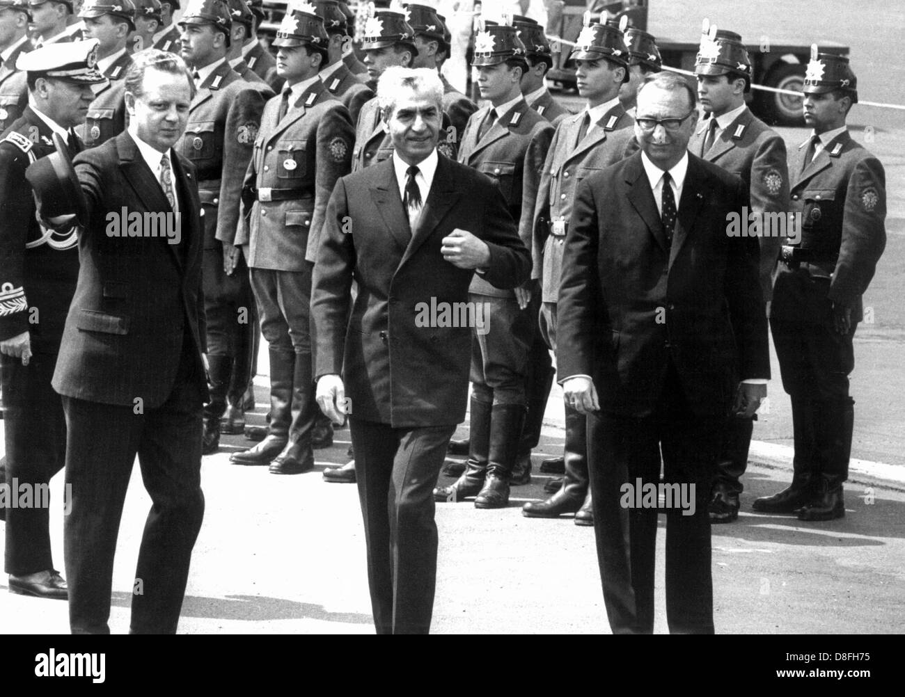 Iranian Shah Reza Mohammed Pahlavi (m), governing mayor of Berlin Heinrich Albertz (l) and chief of protocol Ruprecht Rauch (l) walk past an honorary formation of the police of Berlin on the 2nd of June in 1967 in airport of Tempelhof in Berlin. The visit of the Shah caused massive protests, during which student Benno Ohnesorg lost his life. Stock Photo