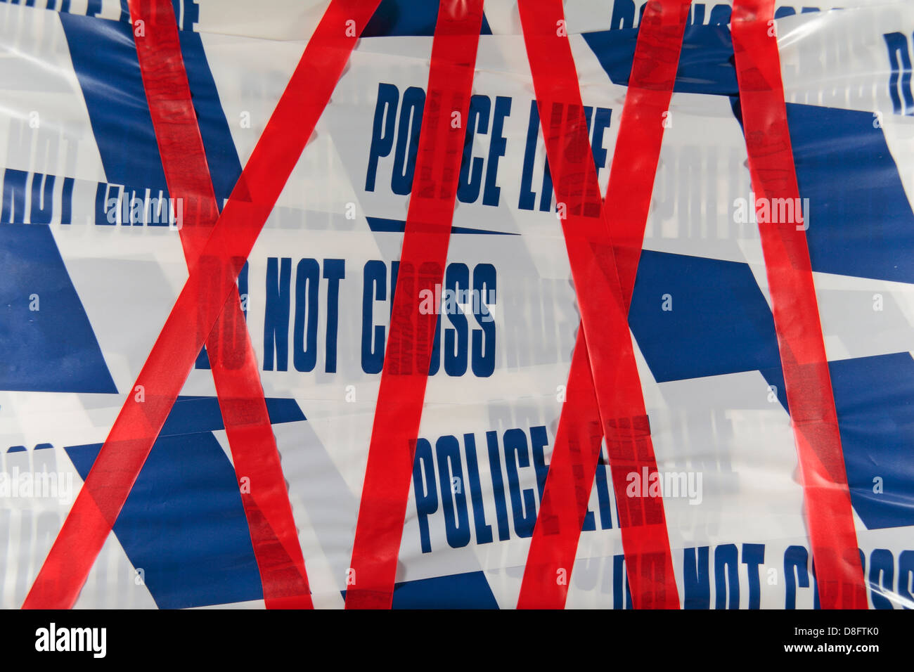 Police Line (Do Not Cross) tape from the United Kingdom (UK) covered with red tape. May 2013 Stock Photo