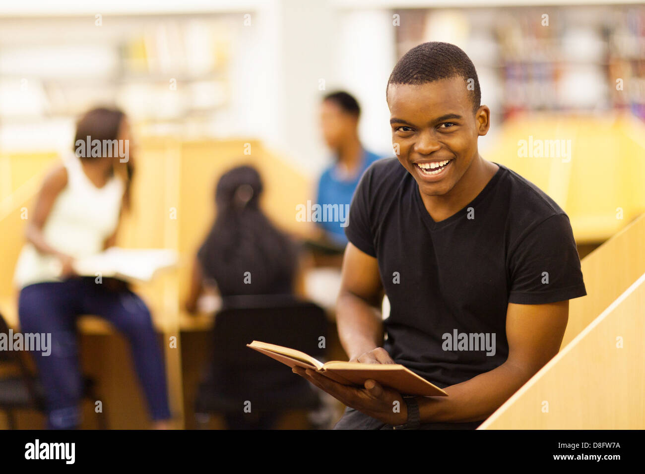 happy male African college student reading book in library Stock Photo