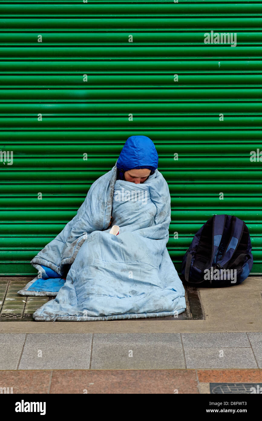 Homeless person  wrapped in a sleeping bag in the shopping area, Henry Street, Dublin city centre  during an economic recession Stock Photo