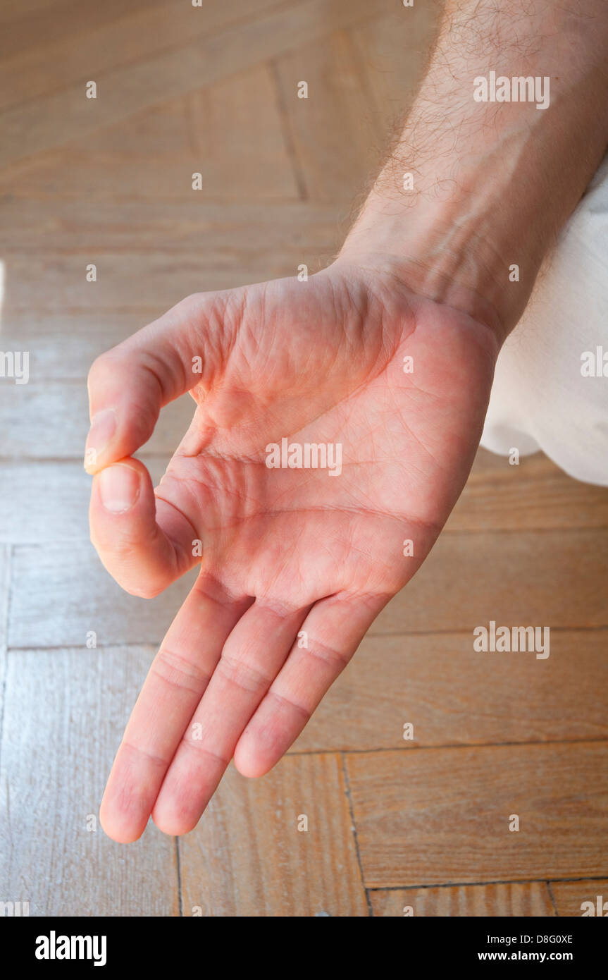 Close view of man's hand practicing yoga, sitting in the lotus position. Stock Photo