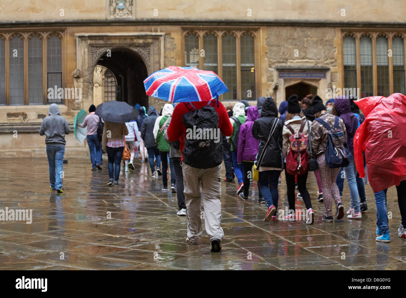 tourists in the rain outside the Bodleian Library Old Schools Quadrangle Oxford University, Oxford, Oxfordshire UK on a wet rainy day in May Stock Photo