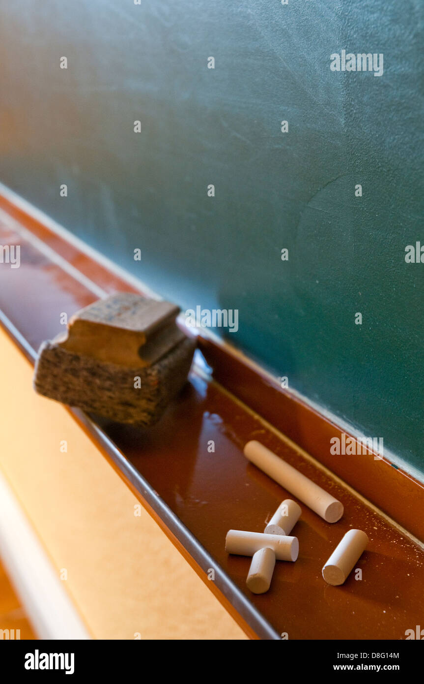 Chalks, duster and blackboard in a classroom. Stock Photo
