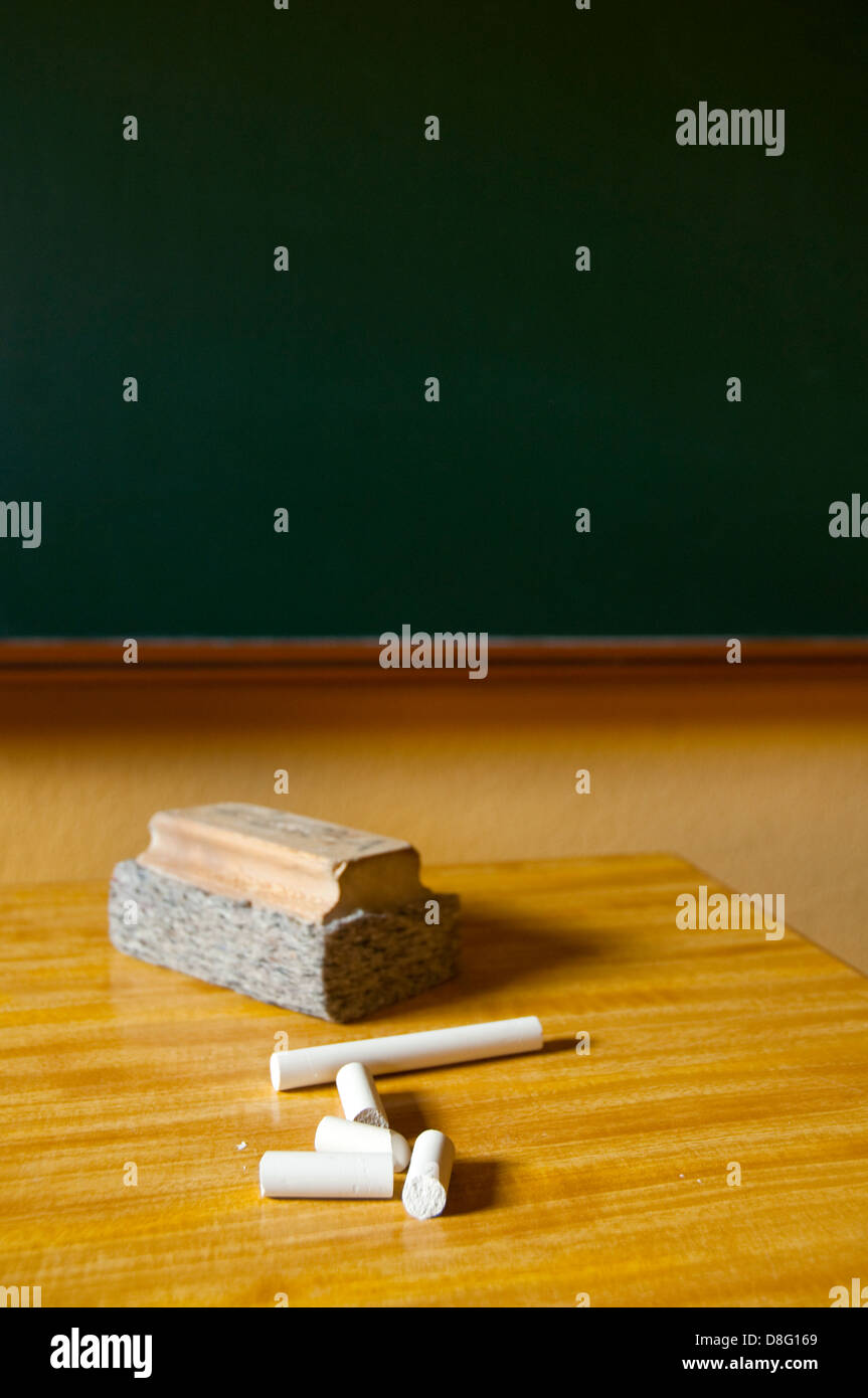 Chalks and duster on the teacher's table in a classroom. Stock Photo