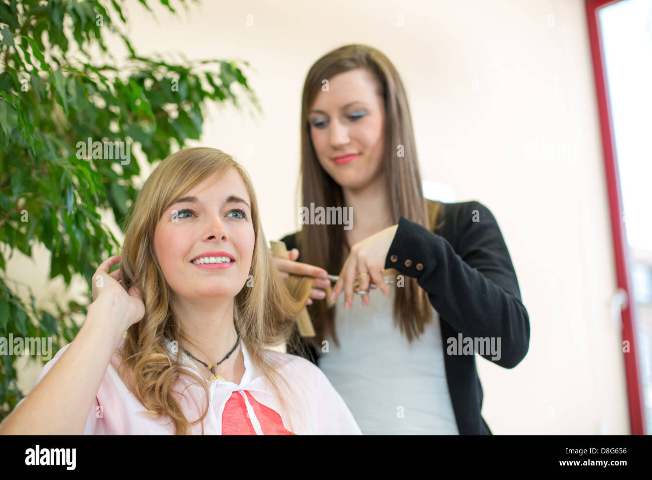 Happy customer getting her hair cut by hairdresser or stylist in salon Stock Photo