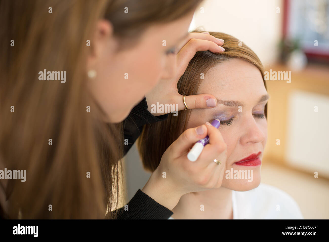Cosmetician applying eye shadow to customer Stock Photo