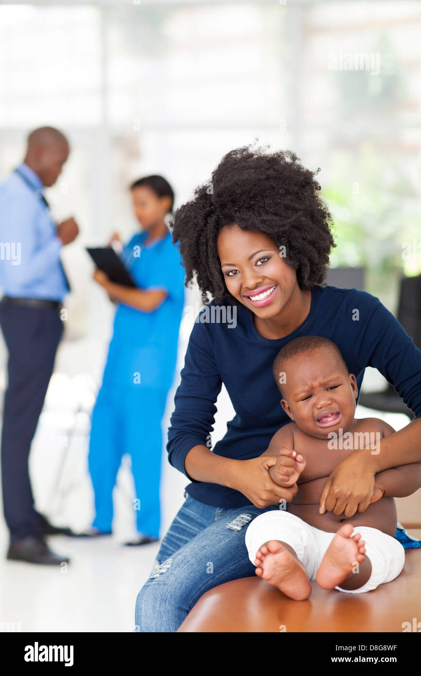 African mother and her sick baby boy waiting for checkup in doctor's room Stock Photo
