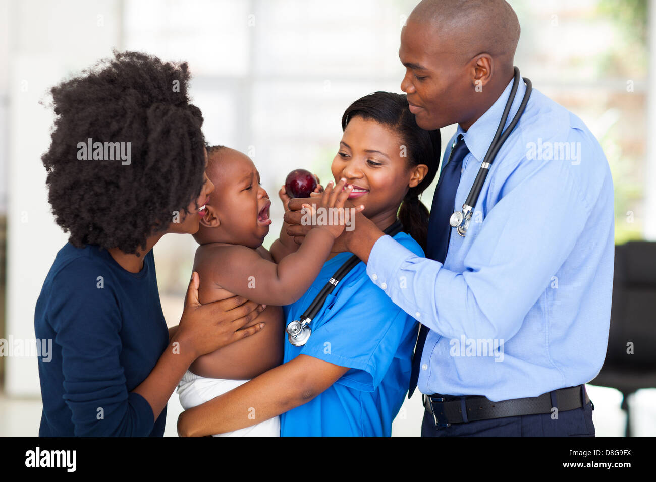 friendly nurse holding crying baby with mother and doctor Stock Photo
