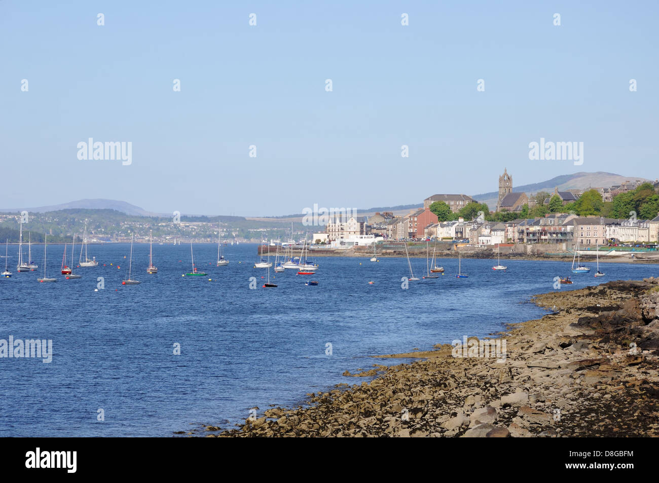 Seafront view of Gourock where small yachts are moored off the rocky shore Stock Photo