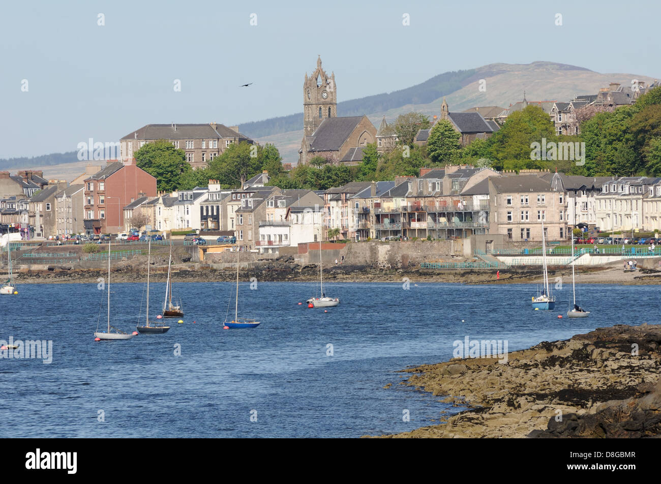Seafront view of Gourock, Scotland, where small yachts are moored off the rocky shore Stock Photo
