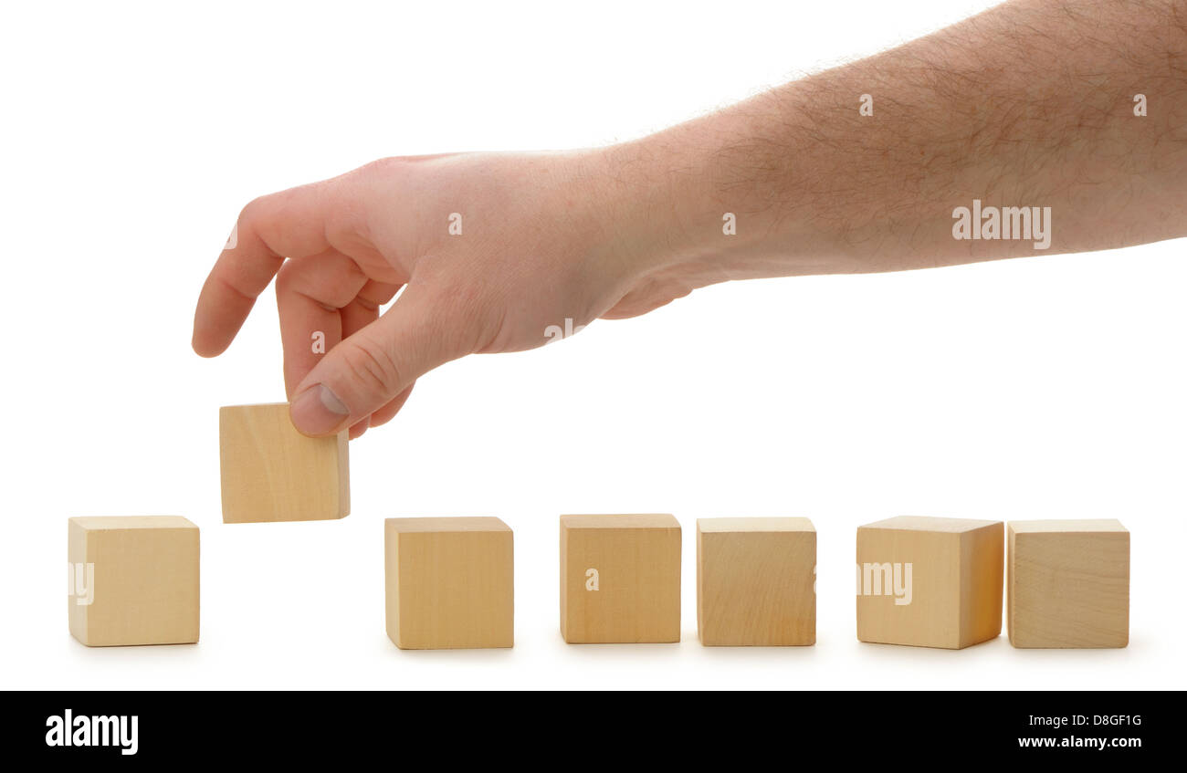 The hand establishes a wooden cube in row Stock Photo