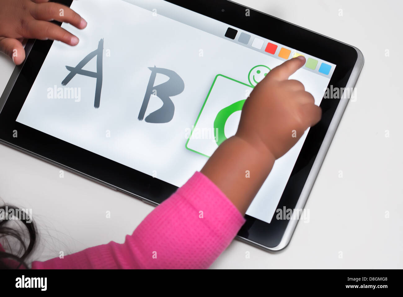 The hand of a child on a touchscreen tablet with educational software. Stock Photo