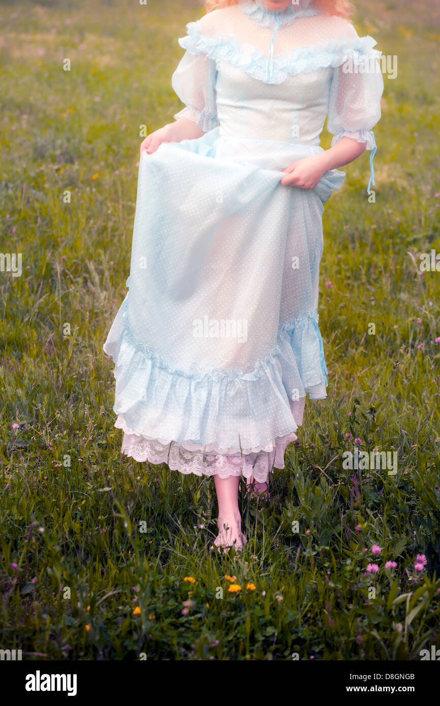 a girl in a vintage dress is running over a meadow Stock Photo