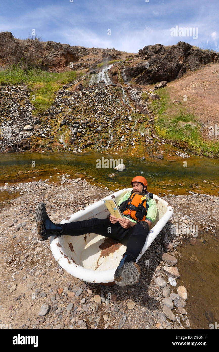 Kayaker reading a river map in a bathtub at Indian Hot Springs along Idaho's Bruneau River. Stock Photo