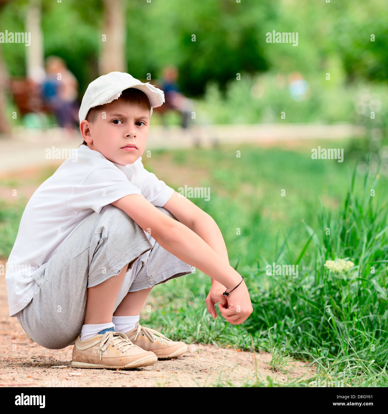 Portrait of boy sitting in a park squat Stock Photo
