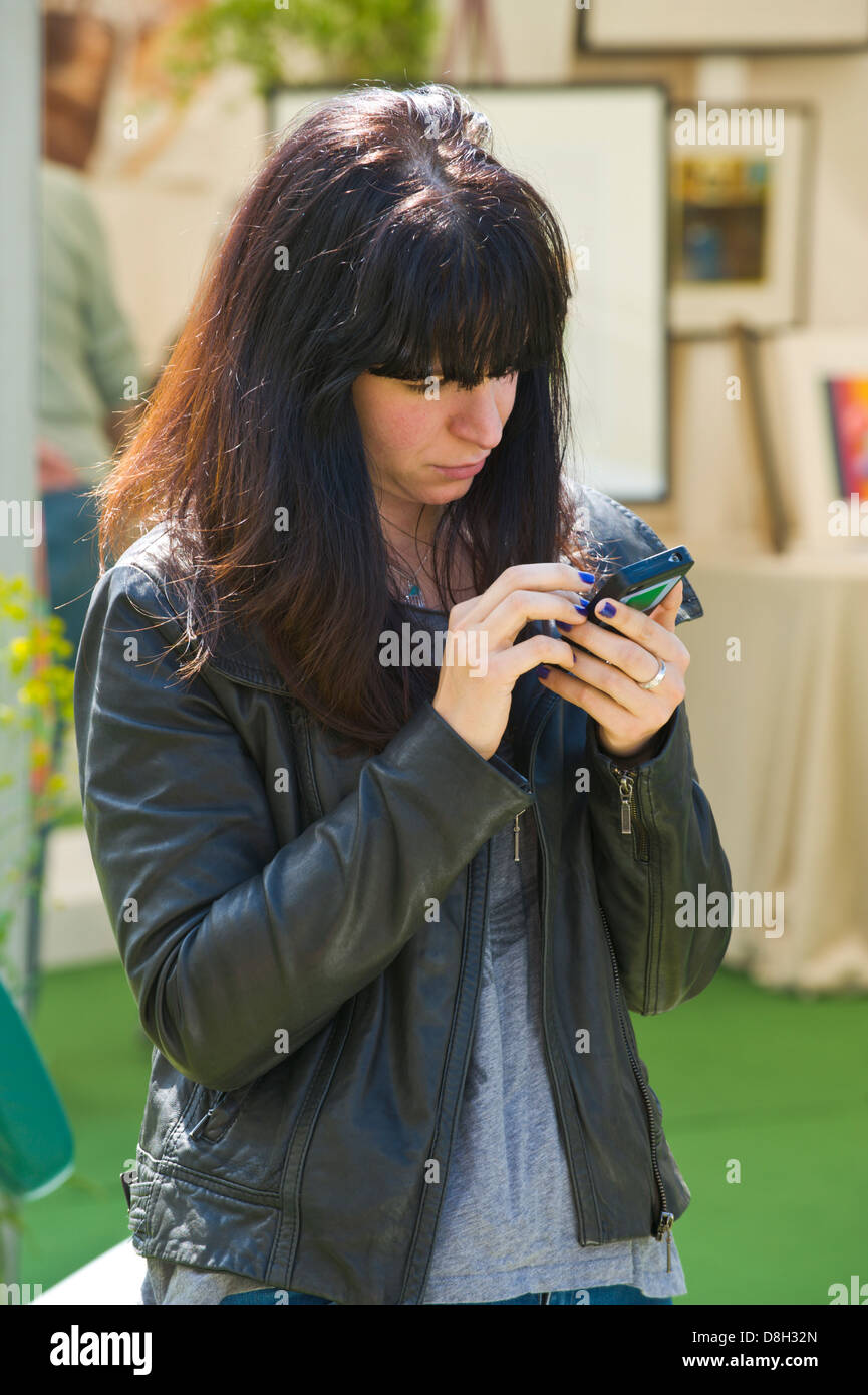 Young woman using smart phone at Hay Festival 2013 Hay on Wye Powys Wales UK Stock Photo