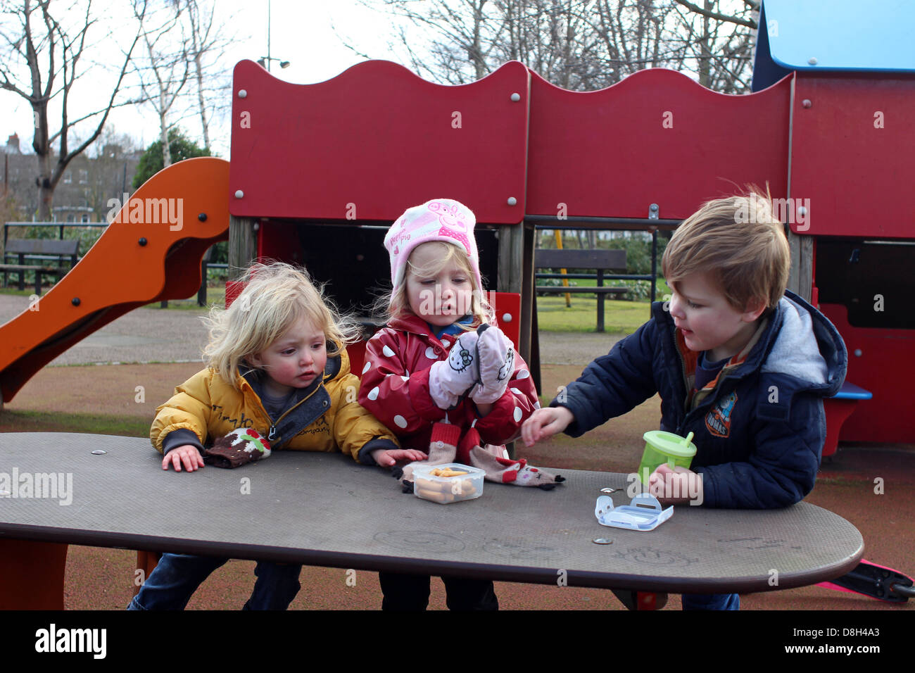 3 children sharing food in the park playground Stock Photo Alamy