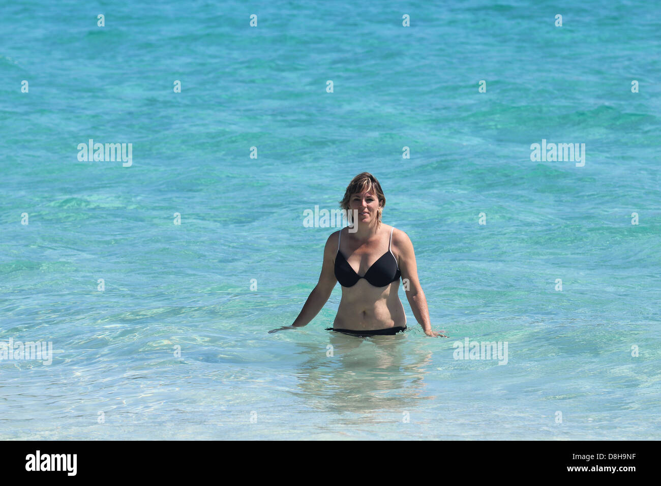 Tropical blue water with middle age woman black bathing suit Stock Photo
