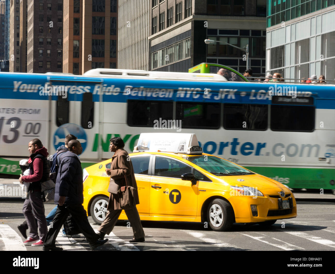 Taxi and Bus in Midtown Intersection with Pedestrians in Crosswalk, NYC Stock Photo