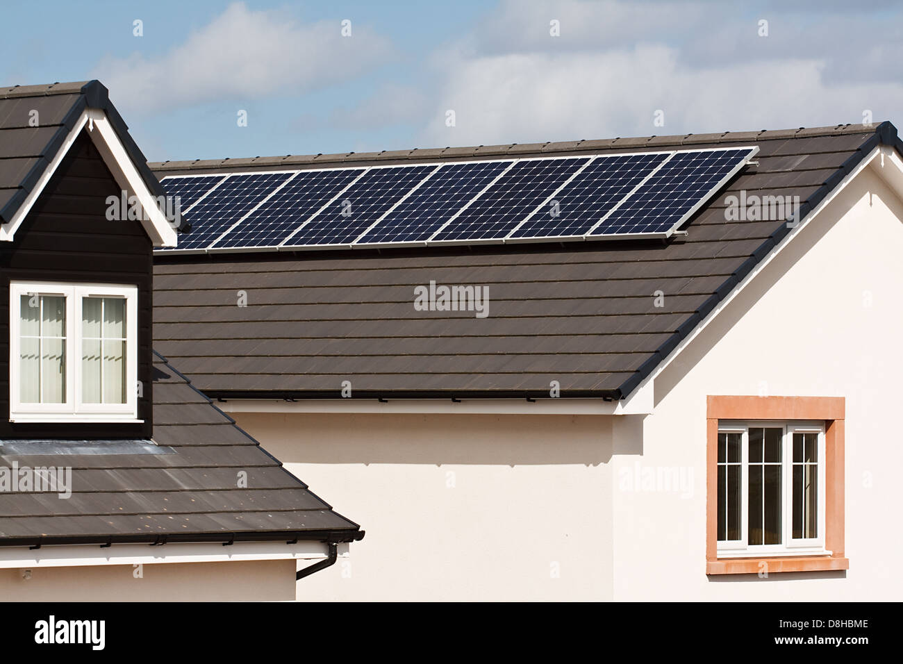 Photovoltaic Solar panels Mounted on the tiled roof of a modern residential or private home Stock Photo