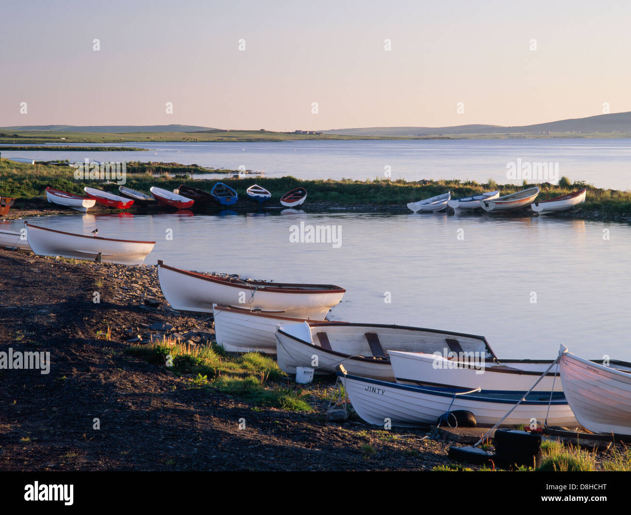 Small fishing boats pulled up on the shore lit by a June sunrise, Loch of Harray, Brodgar, Orkney Mainland, Scotland Stock Photo