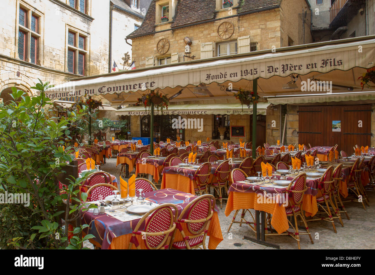 Outdoor courtyard cafe restaurant among medieval sandstone buildings in charming Sarlat, Dordogne region of France Stock Photo