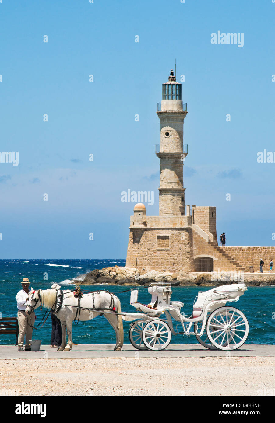 Horse and carriage stands in the Venetian harbour  within Chania, lighthouse in the background. Crete, Greece. Stock Photo