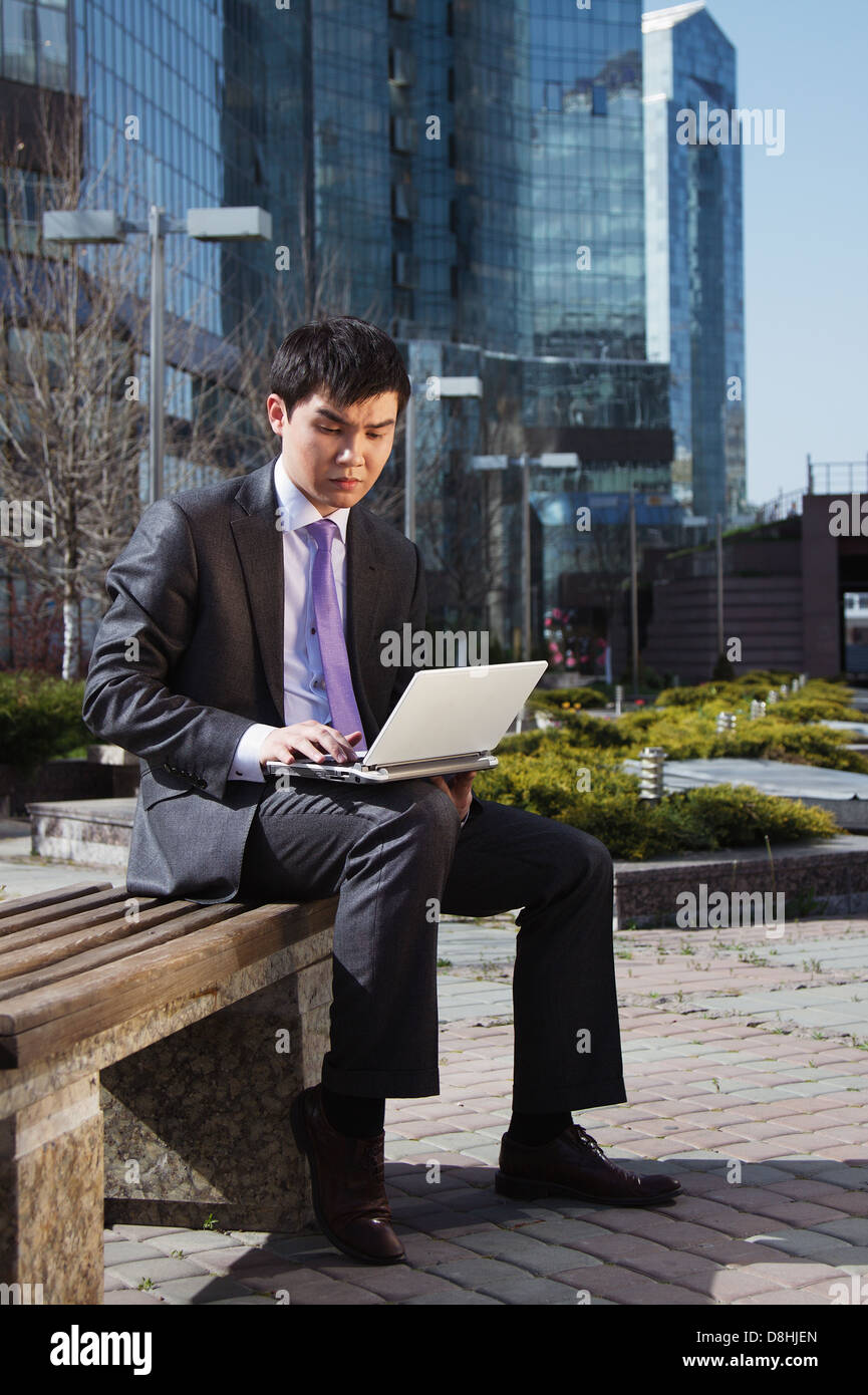 Young businessman sitting with laptop. Outdoor Stock Photo - Alamy