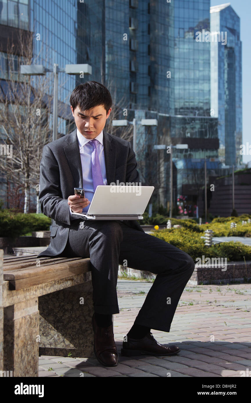 Young businessman sitting with laptop. Outdoor Stock Photo - Alamy