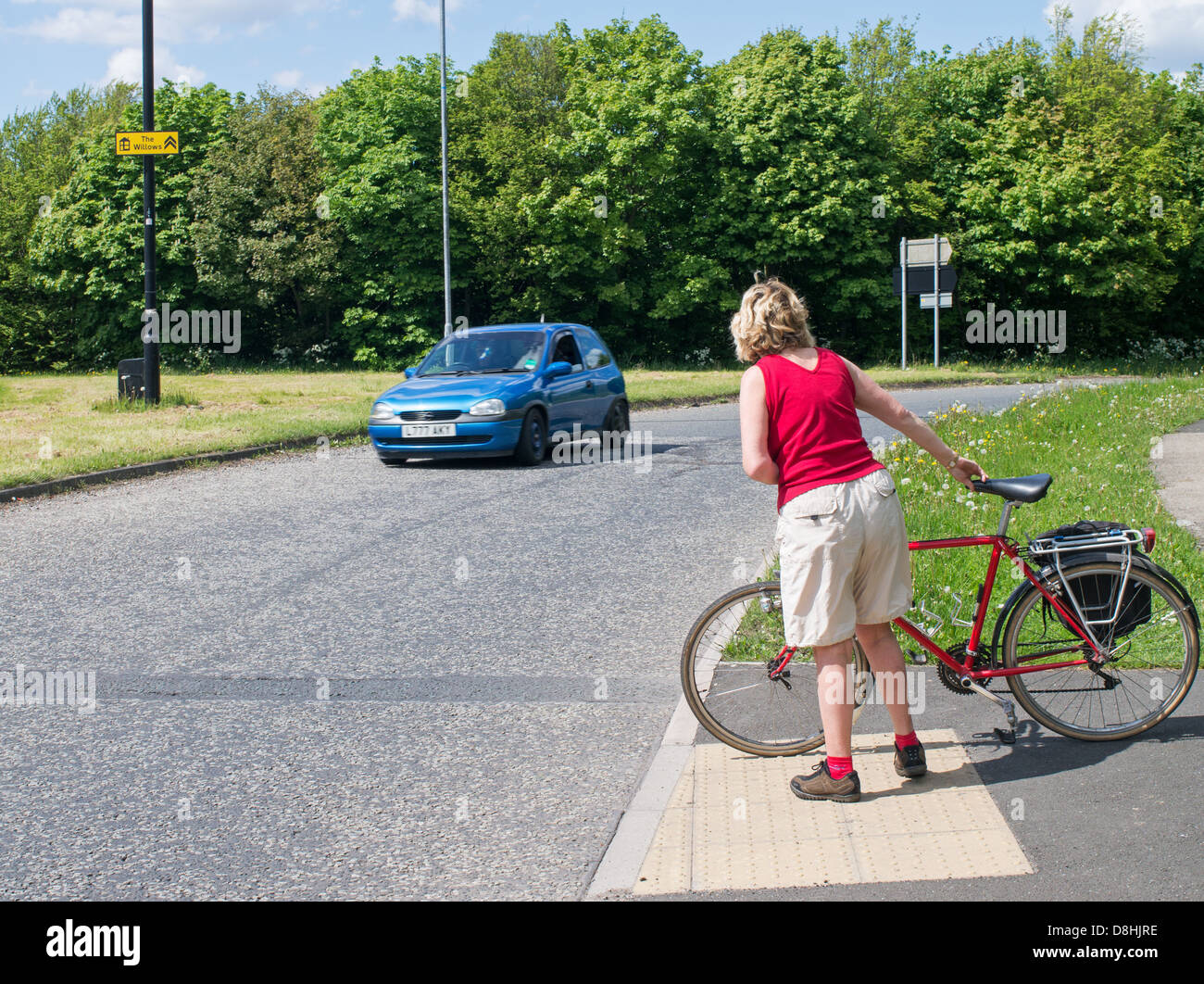 Female cyclist trying to cross the road at a dangerous junction in Washington, north east England UK Stock Photo