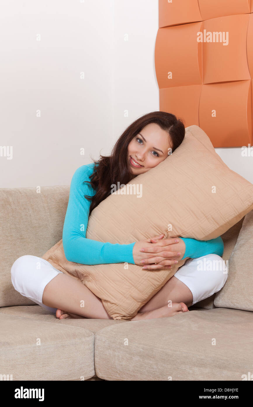 Young woman sitting on a sofa with a pillow Stock Photo Alamy