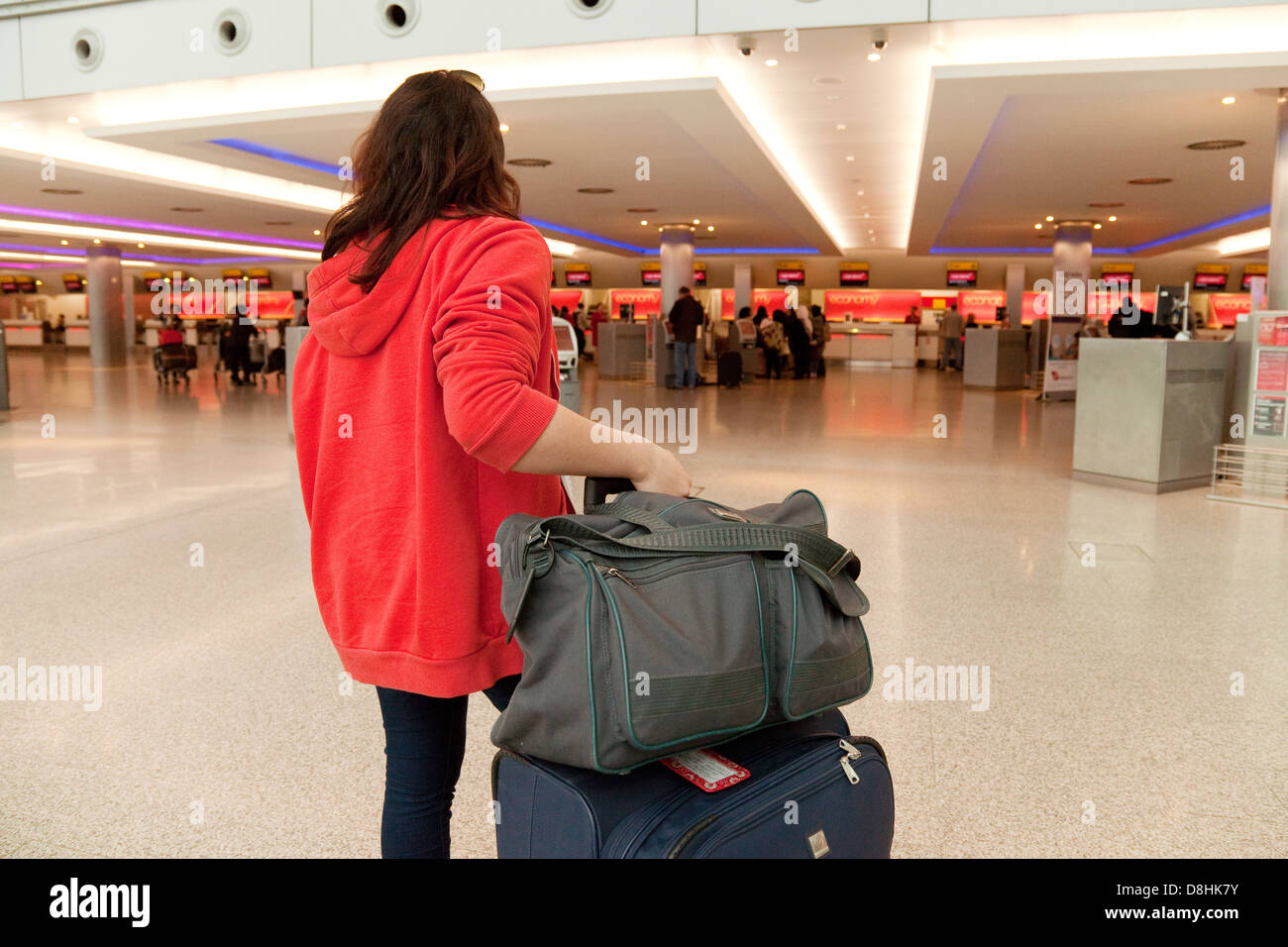 Young woman at airport check in with baggage, Terminal 3, Heathrow airport UK Stock Photo