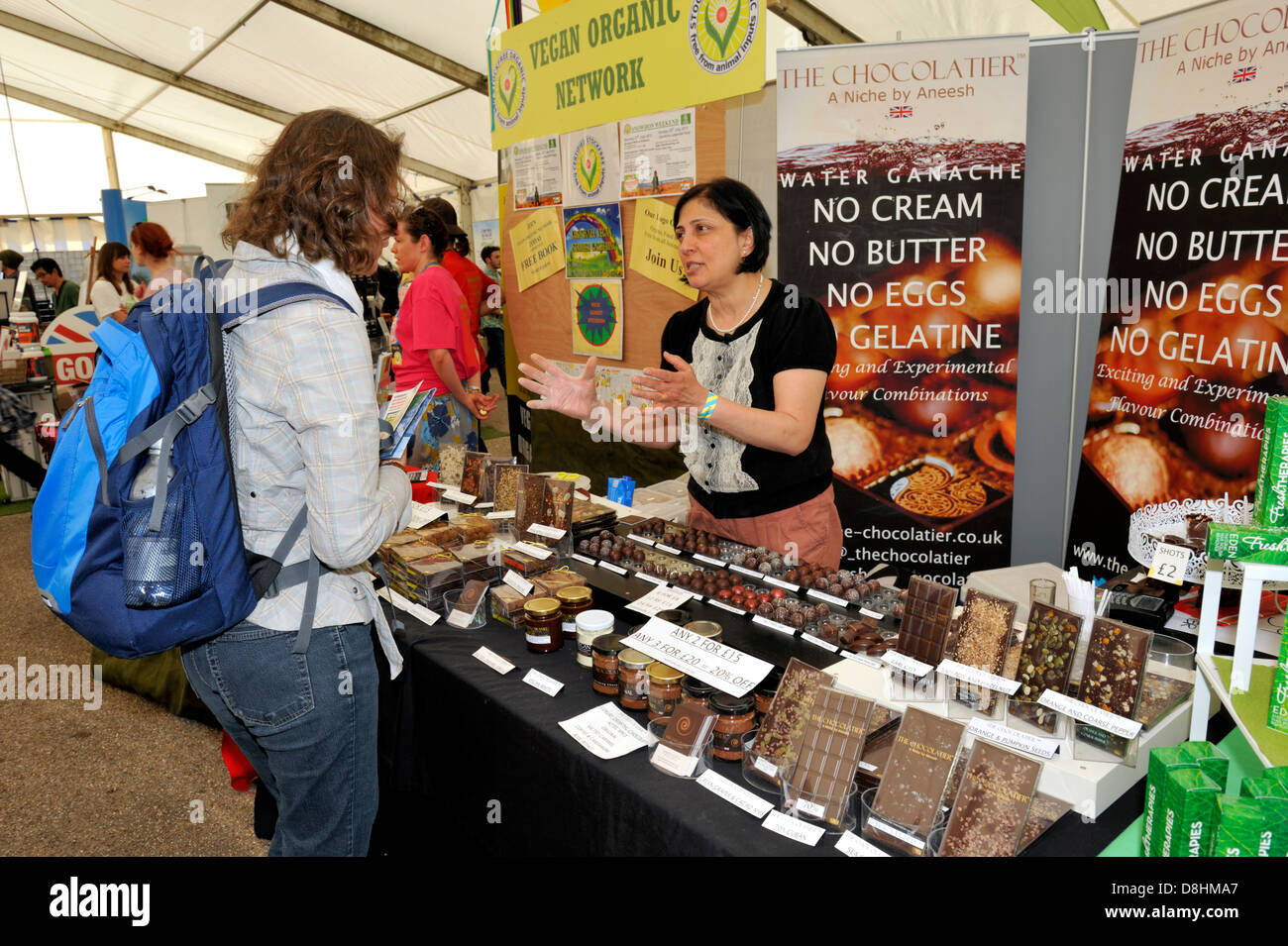 Woman explaining vegan food at festival food stall. Bristol VegfestUK Stock Photo