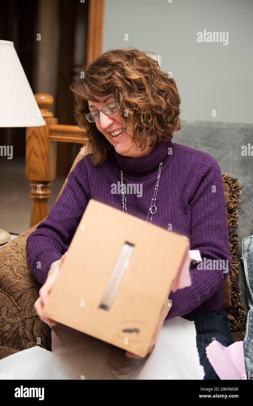 On her 49th birthday, a Caucassian woman opens a birthday gift. Stock Photo