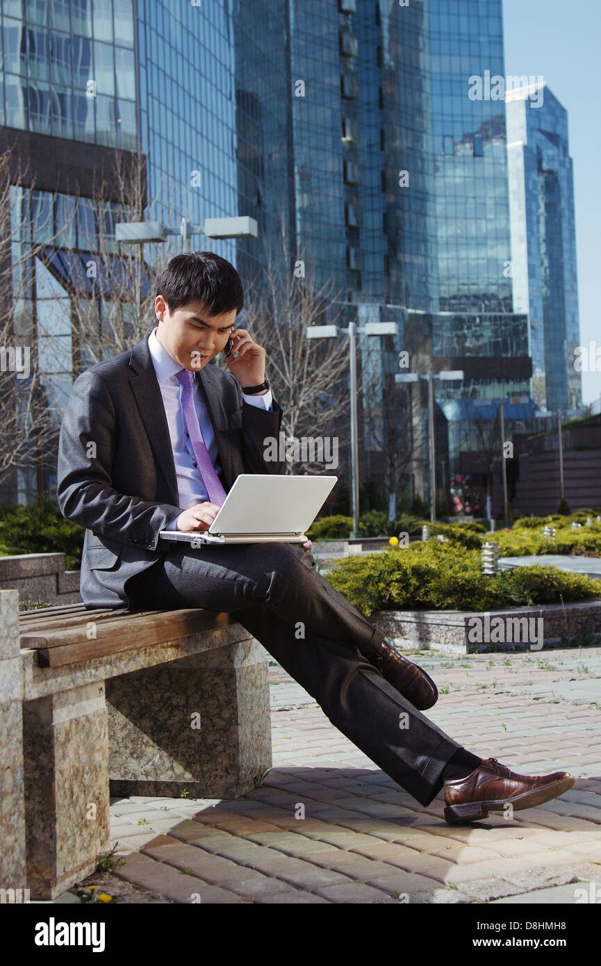 Young businessman sitting with laptop. Outdoor Stock Photo - Alamy