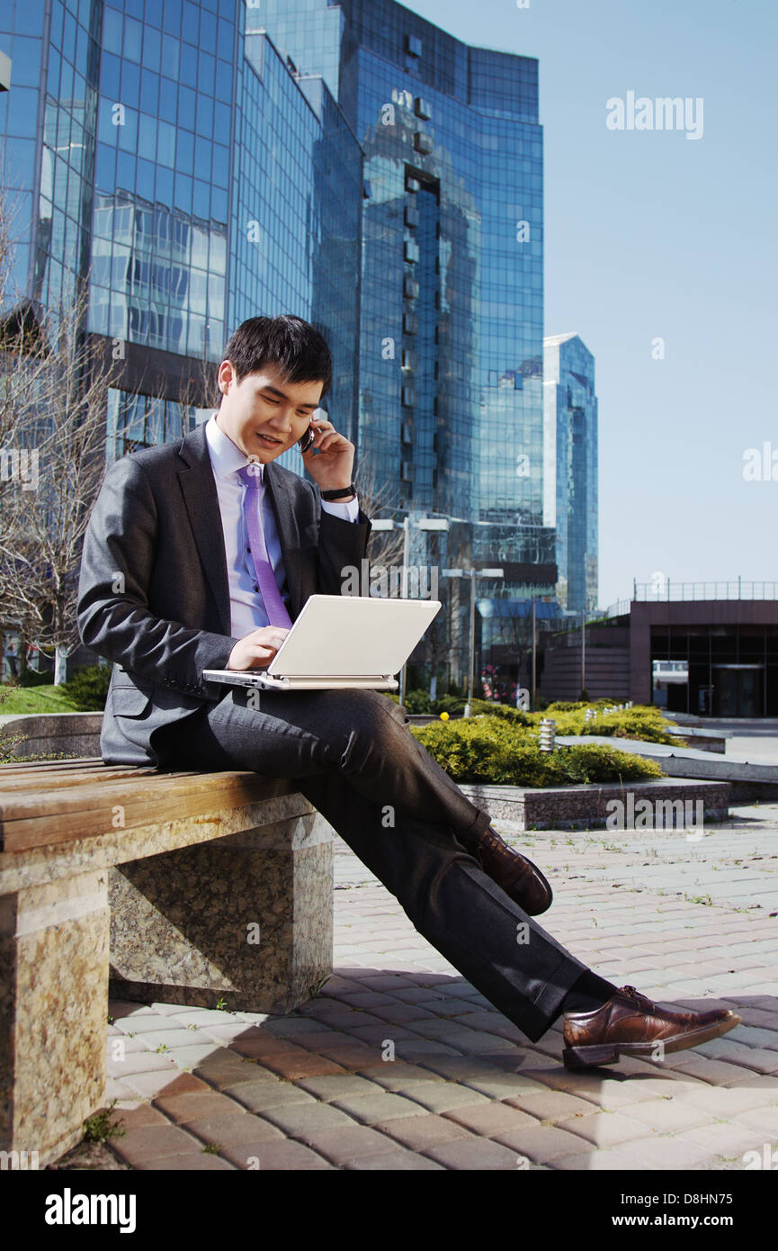 Young businessman sitting with laptop. Outdoor Stock Photo - Alamy