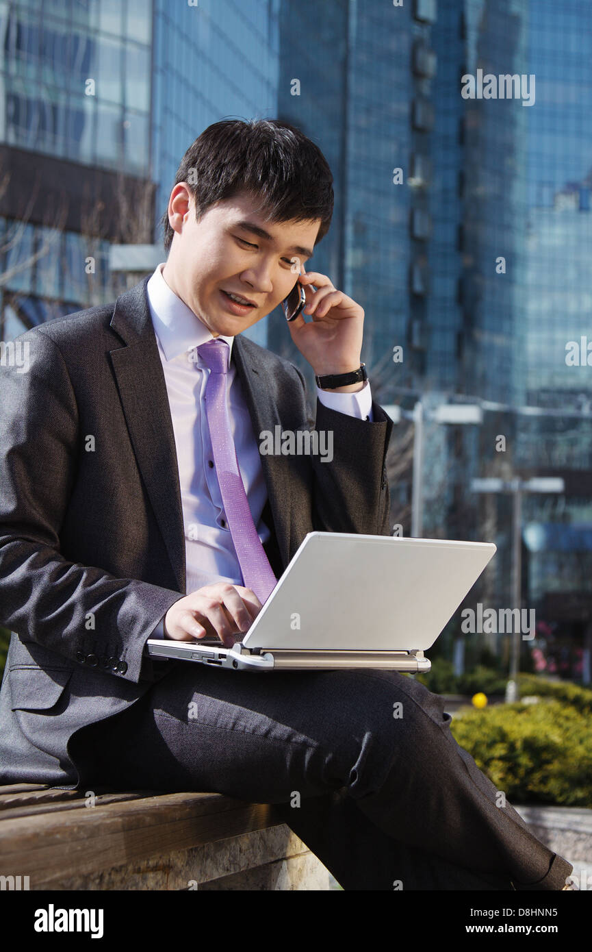 Young businessman sitting with laptop. Outdoor Stock Photo - Alamy