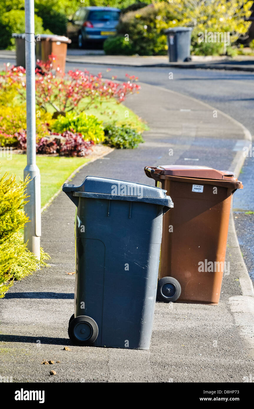 Brown and black recycling wheelie bins spread over a pedestrian footpath Stock Photo