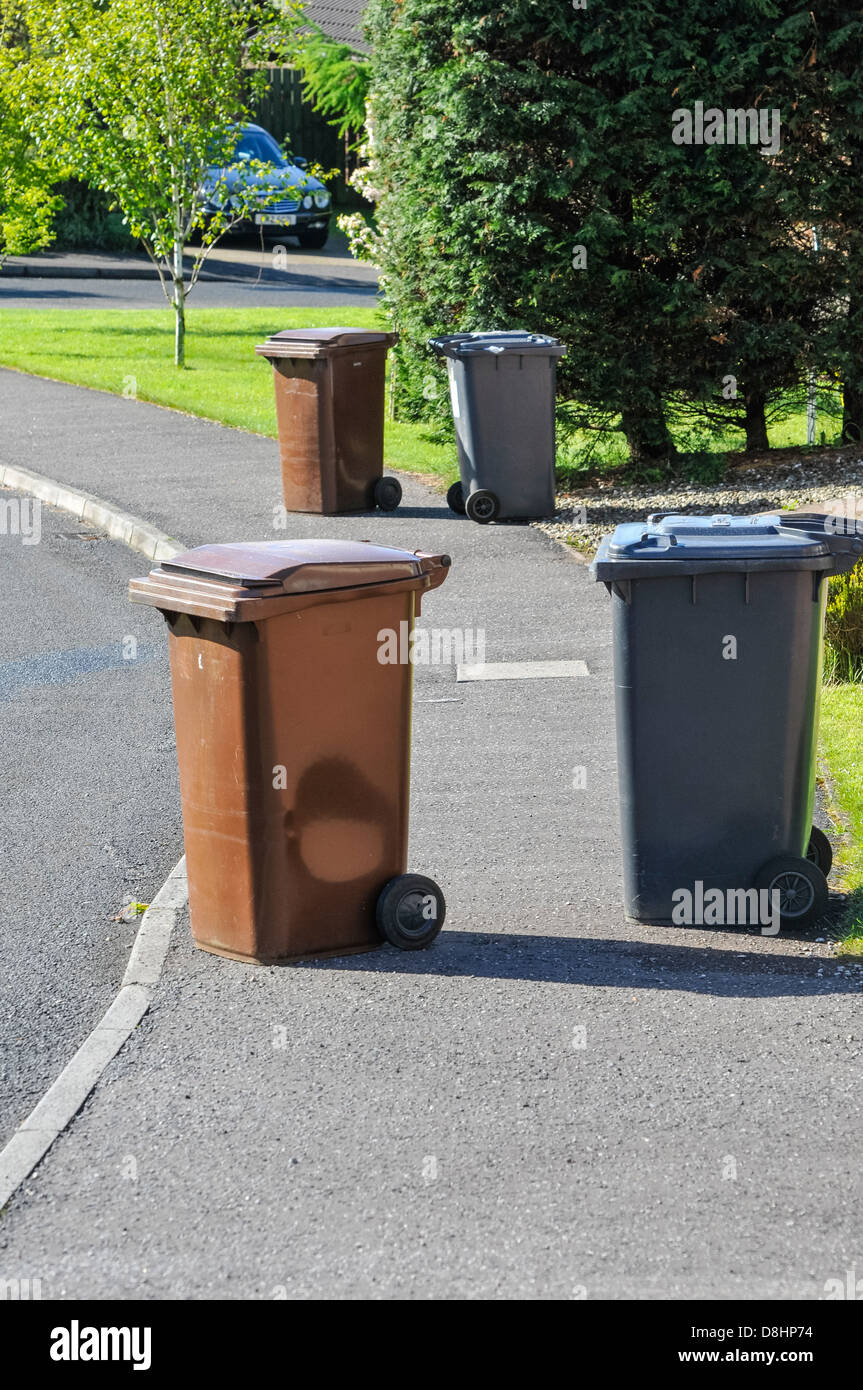Brown and black recycling wheelie bins spread over a pedestrian footpath Stock Photo