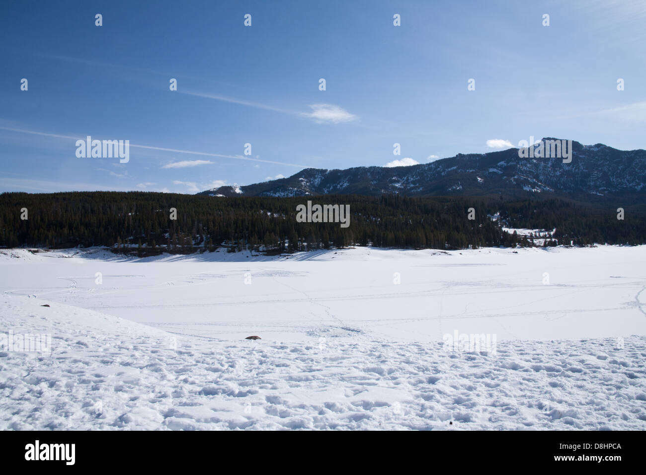 Hyalite Reservoir frozen and covered with snow with boot prints in the foreground. Stock Photo