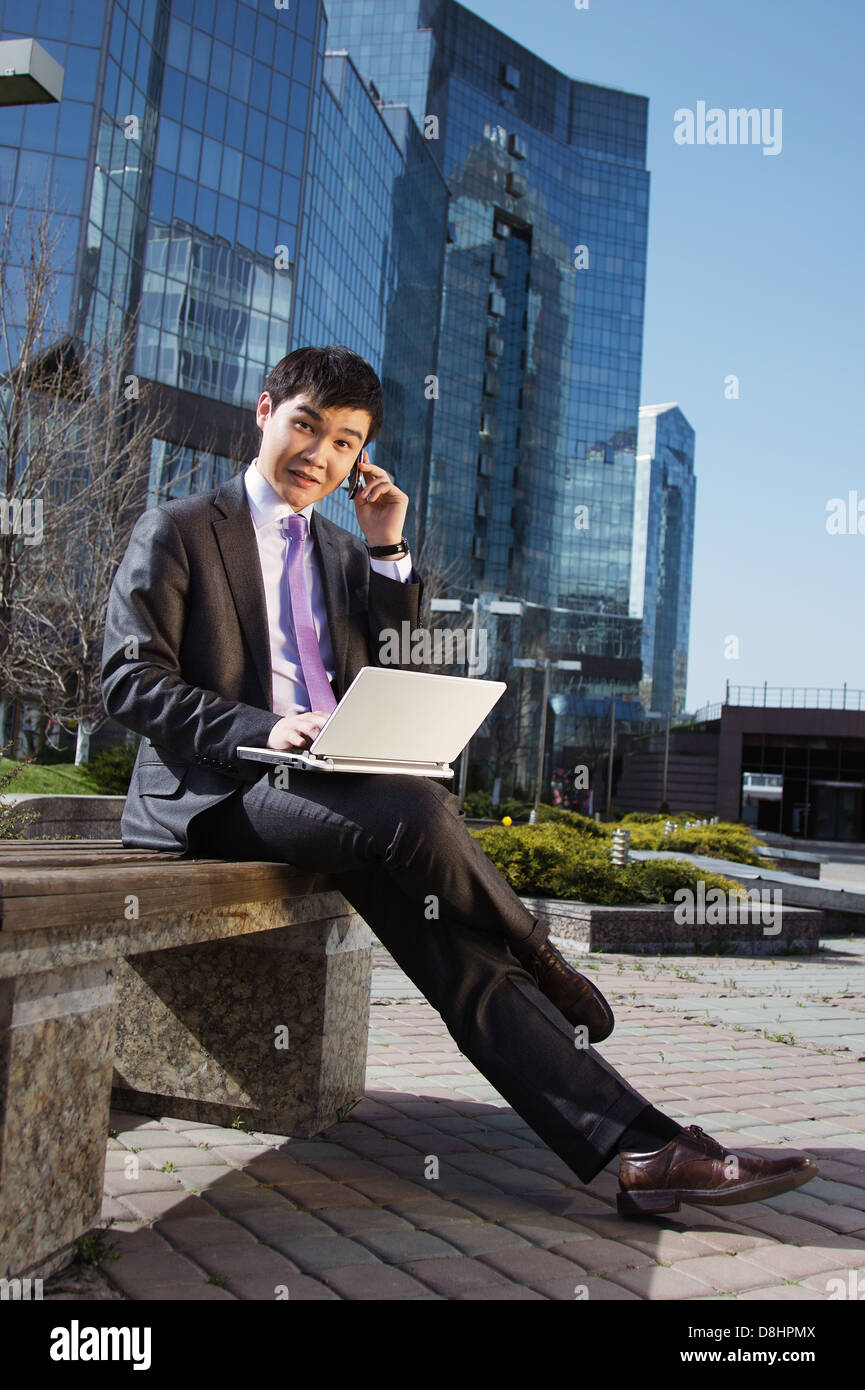Young businessman sitting with laptop. Outdoor Stock Photo - Alamy